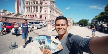 Alex Alves com alguns livros em uma selfie em frente ao TeatroAmazonas